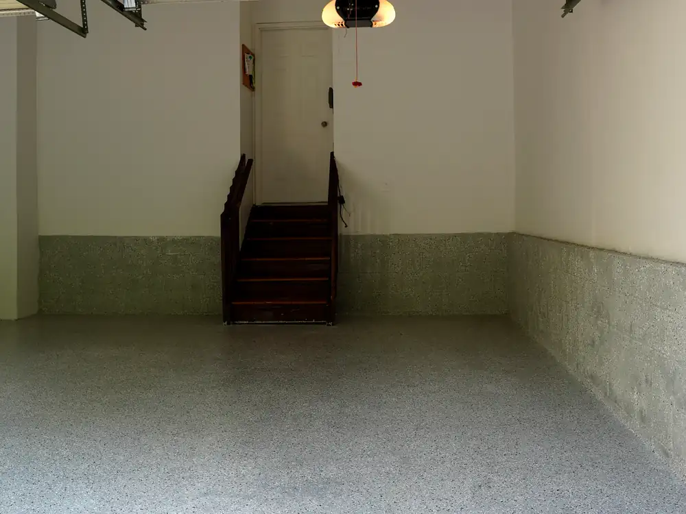Finished garage with grey flake epoxy floor, coated block walls and wood stairs